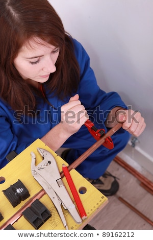 [[stock_photo]]: Female Plumber Cutting Copper Pipe
