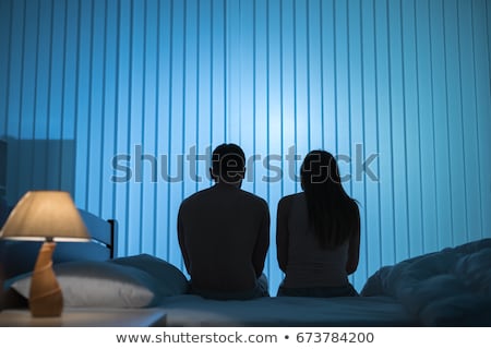 Foto stock: Man Sitting On The Bed With Two Women On The Back