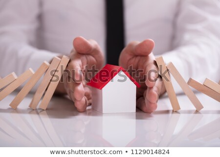 Stockfoto: Businessperson Protecting House Model From Falling Wooden Blocks