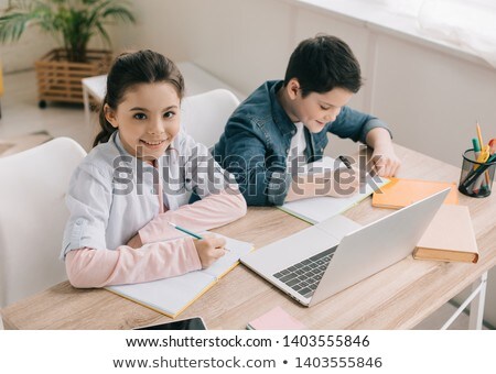 [[stock_photo]]: High Angle View Of Schoolboy Writing On Notebook At Desk In Classroom Of Elementary School