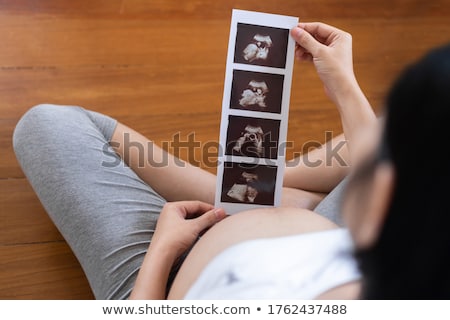 Stock fotó: Pregnant Woman Looking At Ultrasound Scans And Touching Her Bell