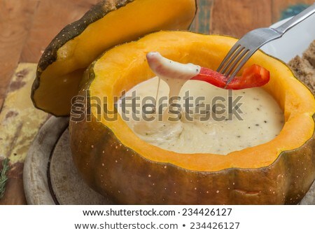 Foto d'archivio: Cheese Fondue In A Roasted Pumpkin With Pepper On A Fork