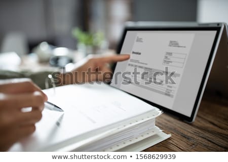 ストックフォト: Businessmans Hands Working On Invoice On Convertible Laptop