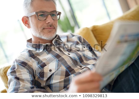 Stock fotó: Man Reading A Newspaper In The Kitchen