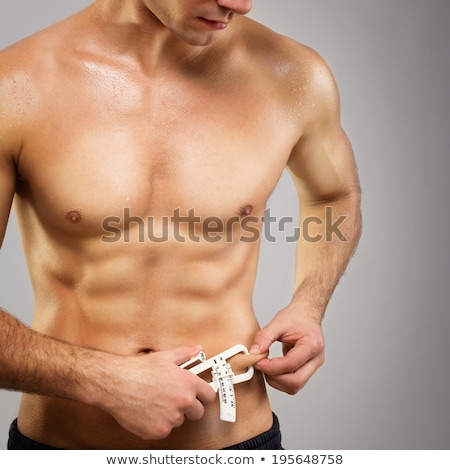 Stockfoto: Muscular Man Measures Level Of Fat On His Body