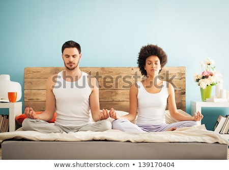 Foto stock: Couple Sitting On Bed In Meditation Pose