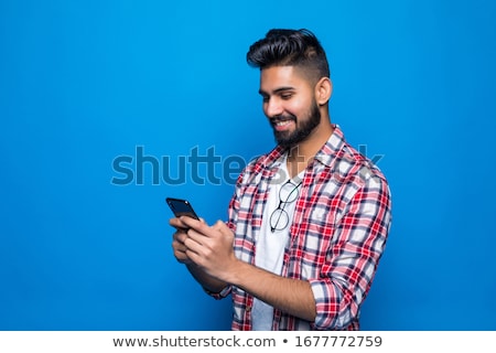 Foto stock: Happy Bearded Man In Shirt Using Smartphone