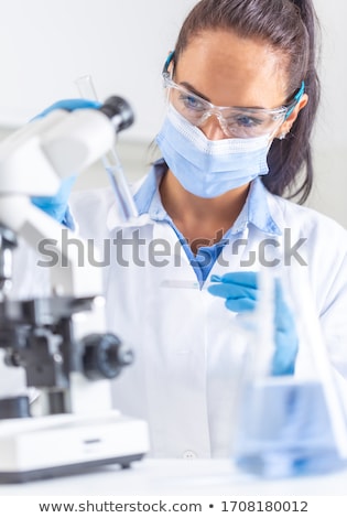 ストックフォト: Woman In White Coat Protective Goggles And Face Mask Looks At T