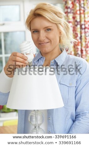 Сток-фото: Woman Putting Low Energy Lightbulb Into Lamp At Home