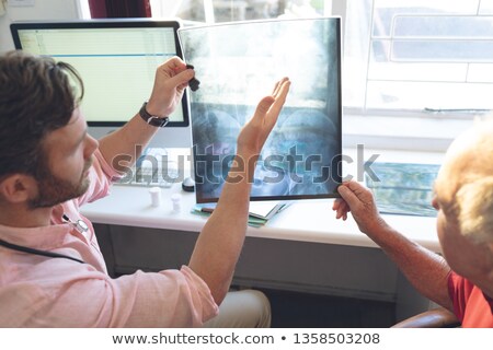 Foto stock: High Angle View Of Confident Caucasian Male Doctor Showing X Ray To Senior Patient In Clinic
