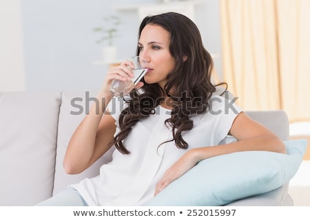 Foto stock: Pretty Brunette Drinking Water On Couch