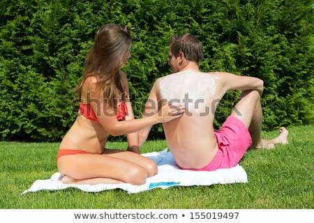 [[stock_photo]]: Woman Applying Suntan Lotion On Mans Back