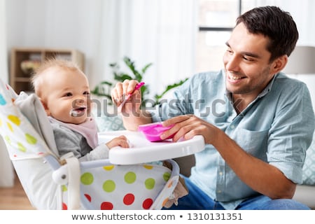 ストックフォト: Father Feeding Happy Baby In Highchair At Home