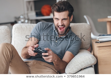 Stockfoto: Concentrated Man Sitting At Home Indoors Play Games With Joystick