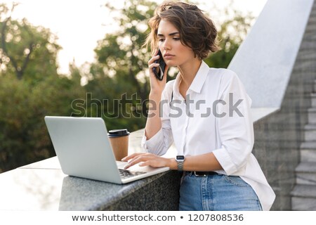 Stock fotó: Displeased Beautiful Woman Standing Outdoors Using Laptop Computer Talking By Phone