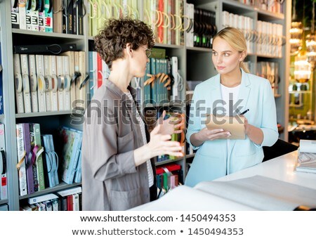 Foto stock: Young Owner Of Design Studio With Pen And Notepad Listening To Female Client