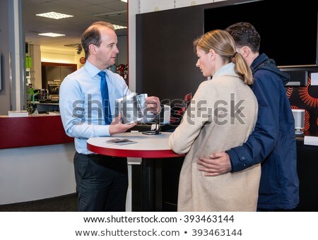 [[stock_photo]]: Assistant Showing Compact Speaker To Couple In Shop