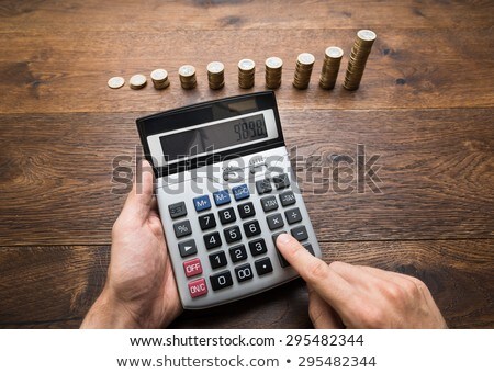 Stok fotoğraf: Person Doing Calculation With Stacked Coins