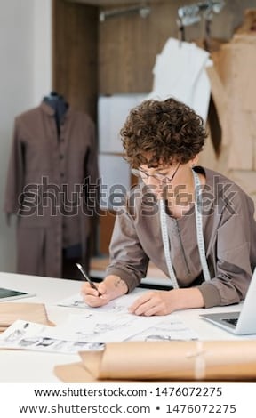 Young Brunette Female Bending Over Desk While Making Fashion Sketches Foto stock © Pressmaster