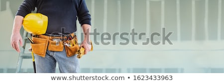 Stok fotoğraf: Contractor With Toolbelt And Hard Hat In Front Of Drywall Banner