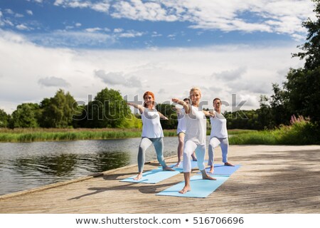 Foto stock: Woman Making Yoga Warrior Pose On Mat Outdoors