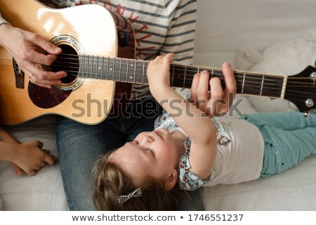 Stock photo: Young Father Teaching His Little Daughter To Play Guitar While S