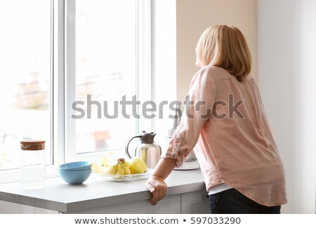 Foto stock: Thoughtful Mature Woman By Window