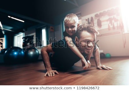 Foto stock: A Boy Lifts Up To A Dumbbell In The Gym