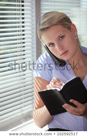 Foto stock: Secretary Talking On The Phone And Looking At Her Agenda