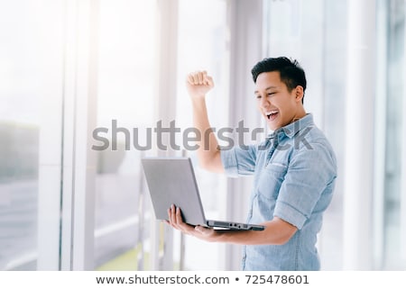 Stock photo: Excited Asian Man Using Laptop