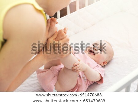 Stock photo: Mother Hold Her Baby Legs In Crib And Having Fun Together