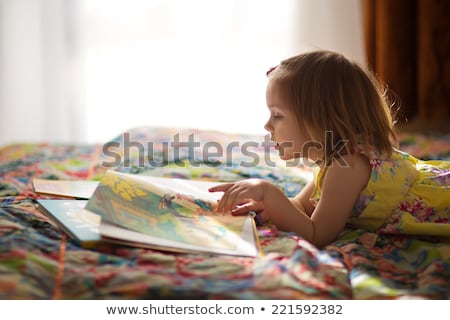 Stockfoto: Little Girl Lying On The Floor Reading A Book