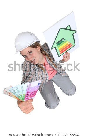 [[stock_photo]]: Tradeswoman Holding Up A Wad Of Cash And An Energy Efficiency Rating Chart