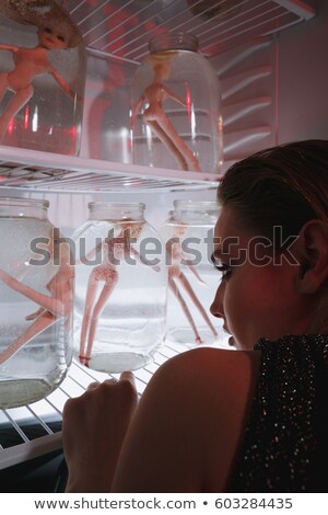 Foto stock: Cropped Image Woman Looking At Fridge With Dolls In Jars