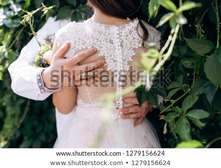 [[stock_photo]]: Couple Standing And Hugging Outdoos Among Bushes