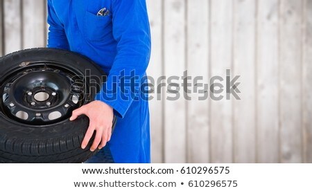 ストックフォト: Mechanic With Tyre Against Blurry Wood Panel