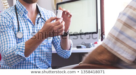 Foto stock: Mid Section Of A Caucasian Male Doctor Prescribing Pills To His Senior Male Patient In Clinic