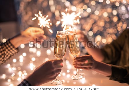 Foto stock: Hands Of Friends Holding Flutes Of Champagne And Sparkling Bengal Lights