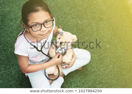 Stok fotoğraf: A Little Girl Playing Doctor With Her Teddy Bear
