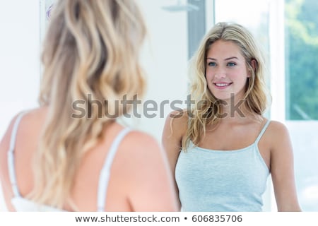 Foto stock: Happy Woman Looks In The Mirror