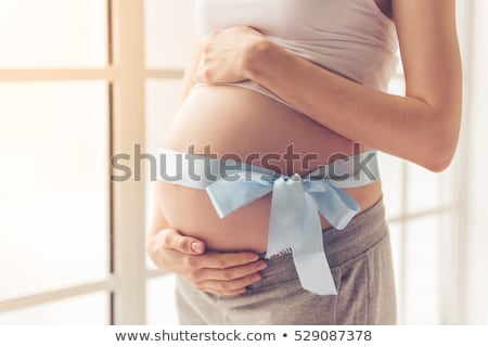 Stok fotoğraf: Pregnant Woman Standing With Hands Hugging Her Belly