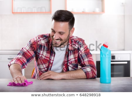 Stock foto: Smiling Man Cleaning Table With Cloth At Home