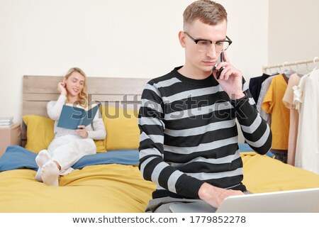 ストックフォト: Young Woman Is Working On A Laptop In His Bed On A Background Of A Panoramic Window Overlooking The