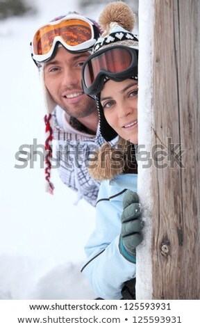 ストックフォト: Young Couple At Ski Resort Hiding Behind Wooden Post