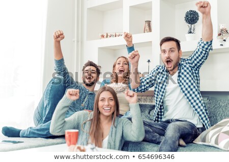 Foto stock: Happy Friends Watching Tv At Home In Evening