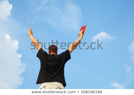 Foto stock: Young Man Staying With Raised Hands Against Blue Sky