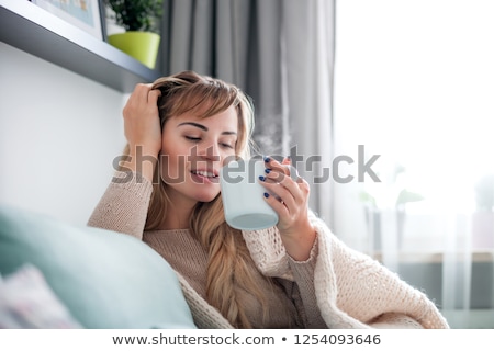 [[stock_photo]]: Cheerful Young Beauty Sitting On The Couch In Bright Room And Smiling Relaxing
