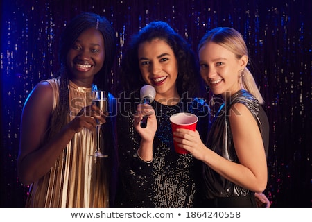 Foto stock: Three Smiling Women Dancing And Singing Karaoke