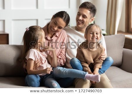 Foto d'archivio: Image Of Young Happy Family Sitting On Sofa At Home And Looking