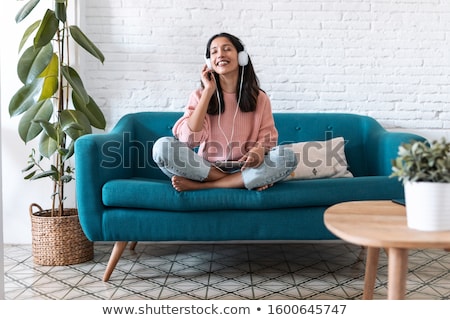 Foto stock: Girl Listening To Relaxing Music In Headphones While Sitting In Pose Of Lotus